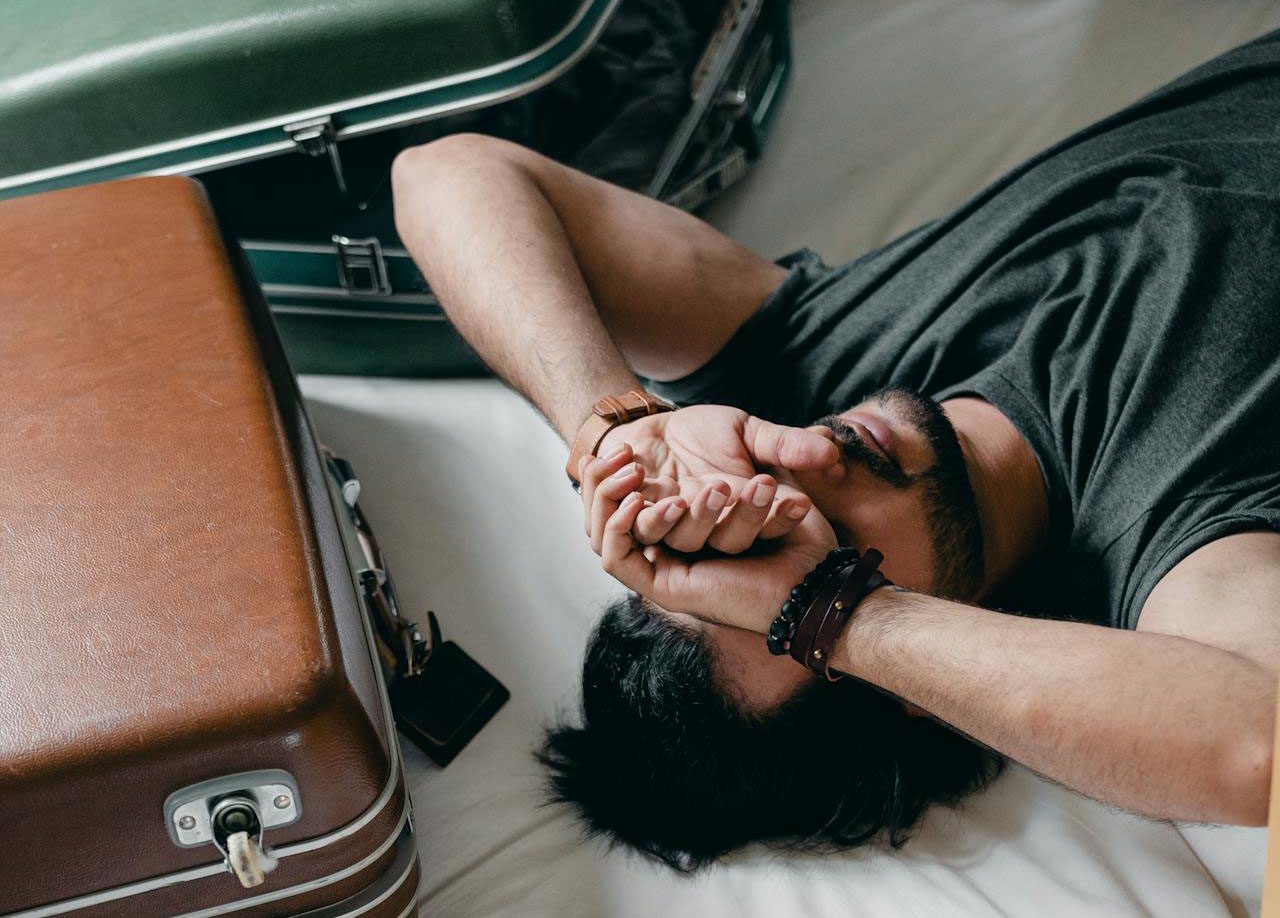 Tired ethnic man lying on bed during relocation in new house